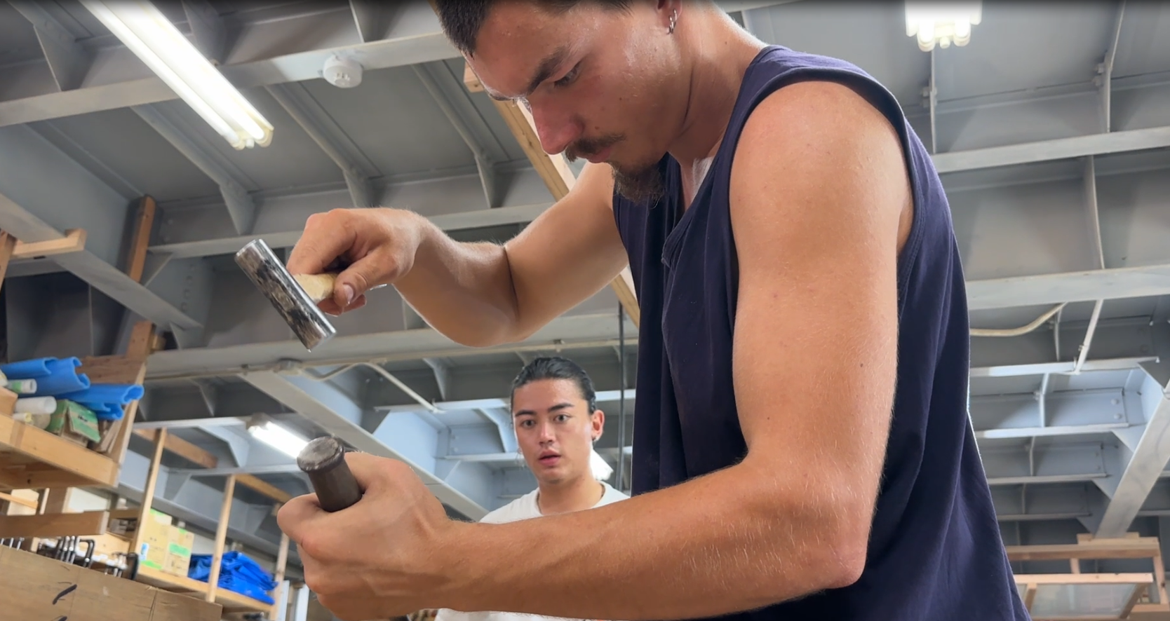 Students at the workbench using a mallet and chisel
